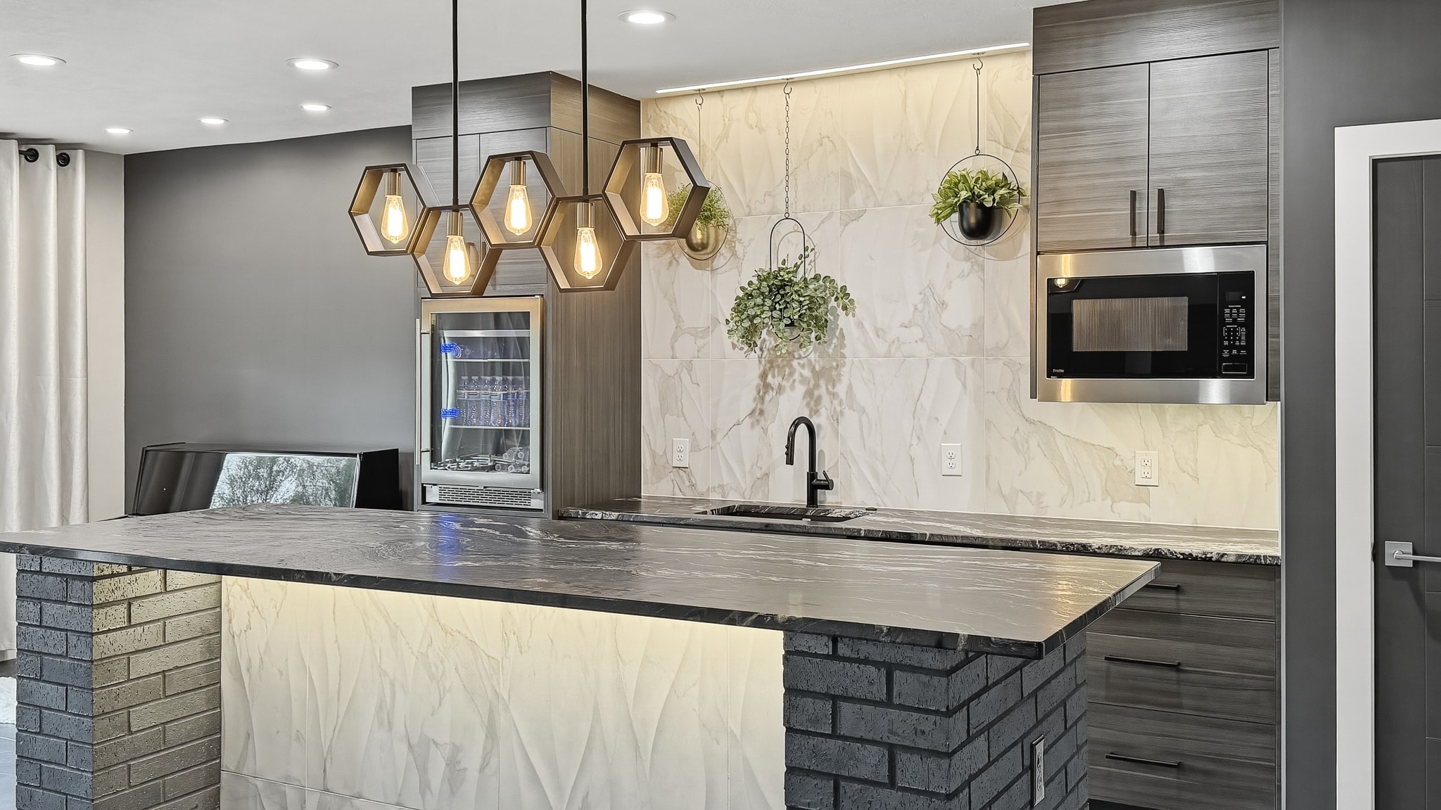 Bar with hexagon pendants, marble tile backsplash, brick columns and dark tile floor