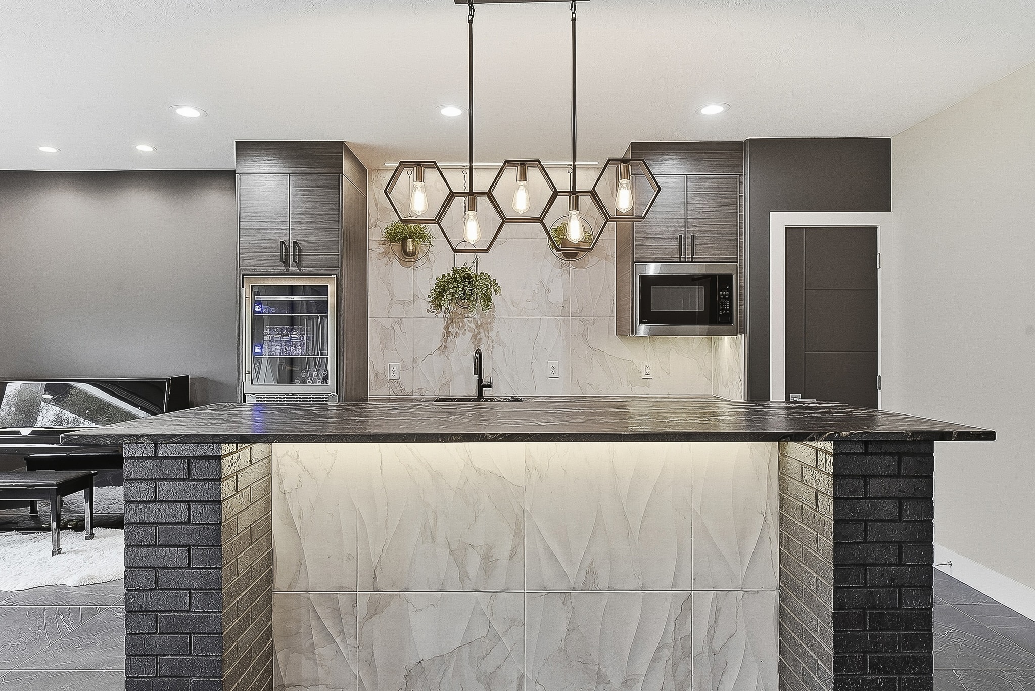 Bar island with hexagon pendants, marble tile backsplash and dark tile floor