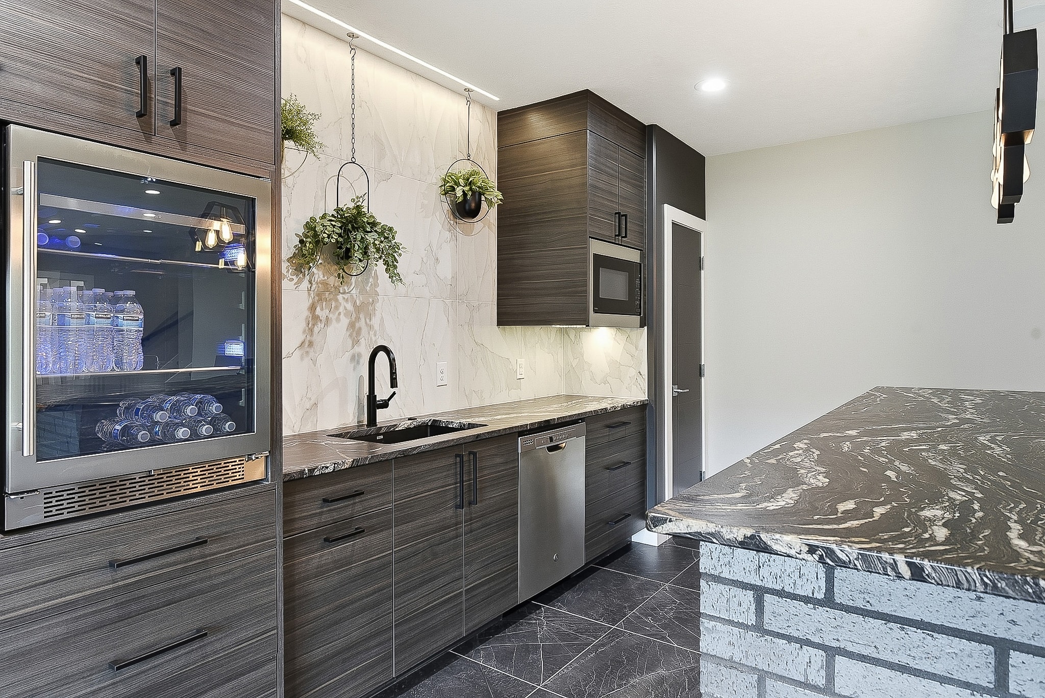 Bar with beverage fridge, marble tile backsplash, dark cabinetry and brick island