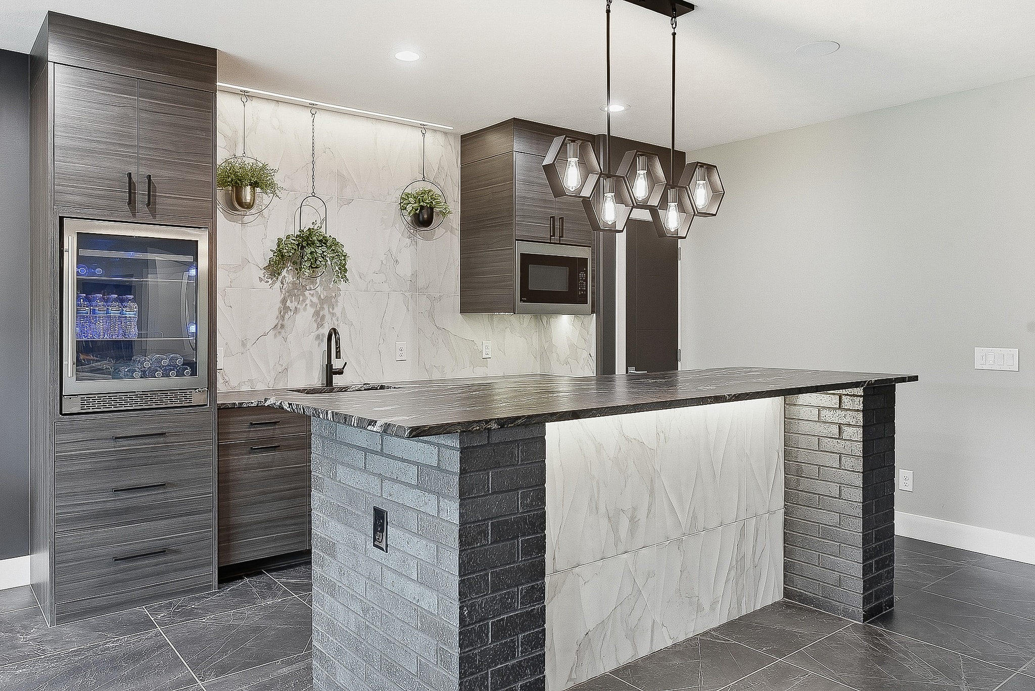 Full bar view with hexagon pendants, marble tile backsplash, brick island and dark tile floor