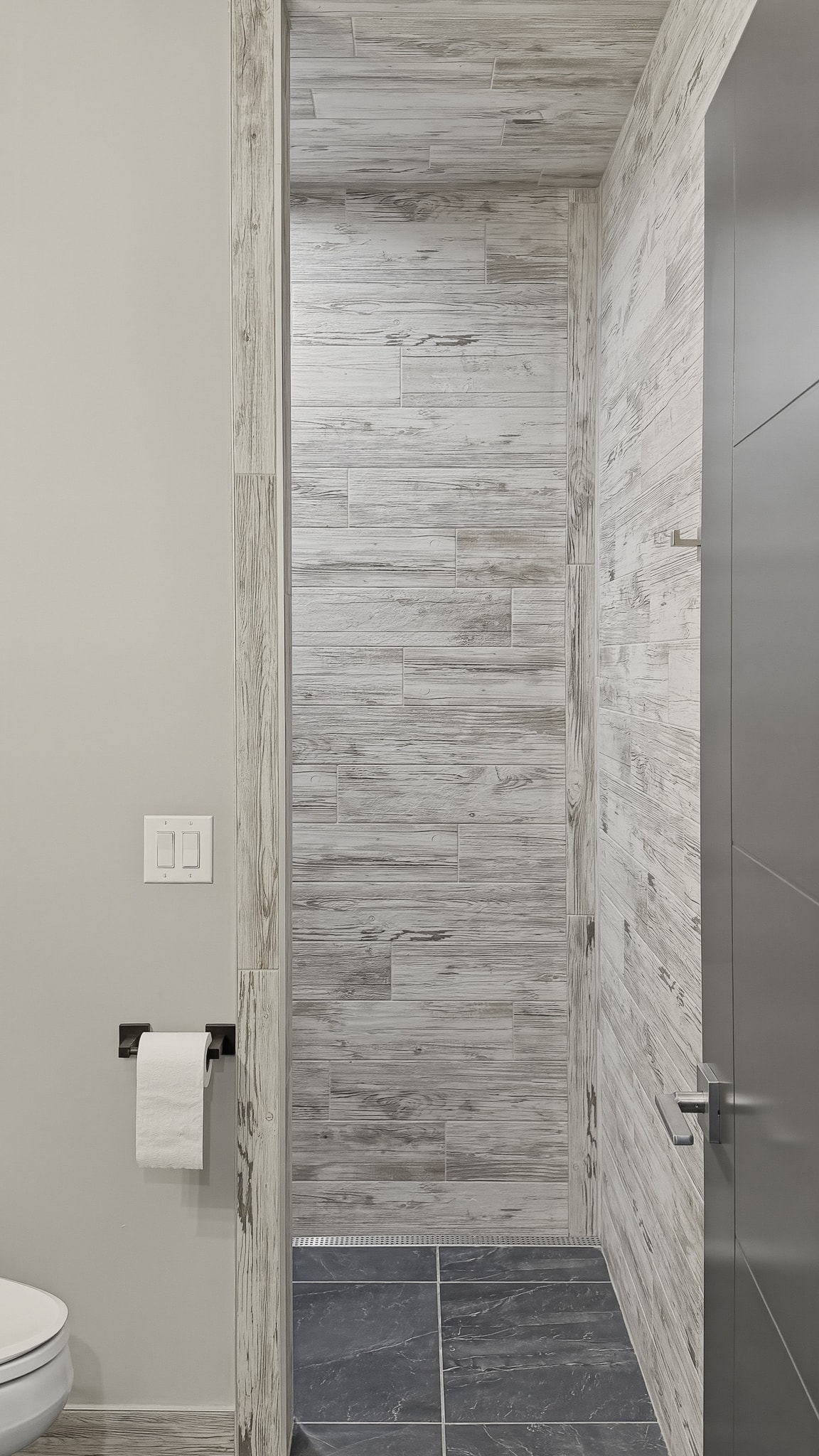 Wood-look tile shower with dark slate floor