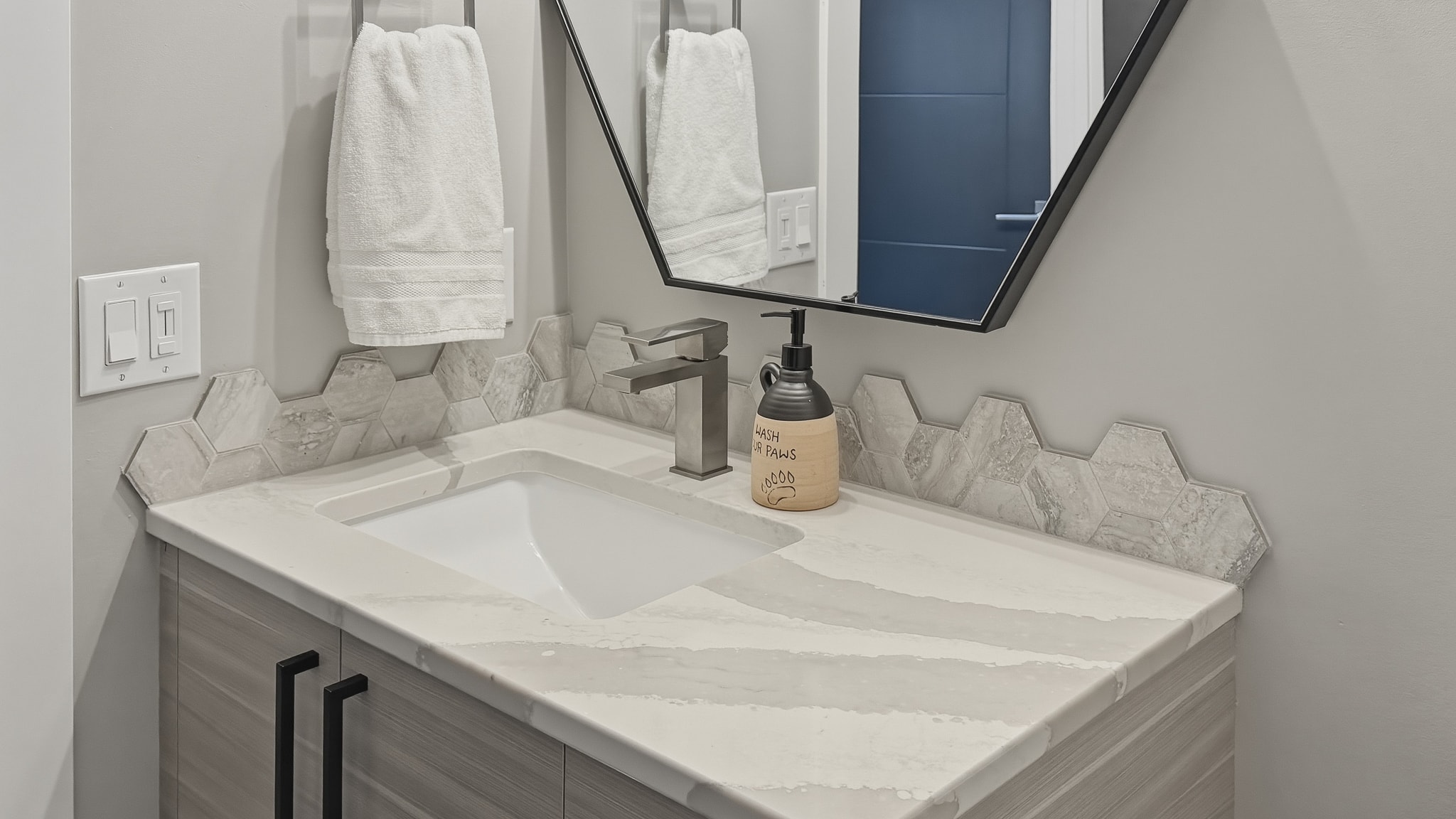 Bathroom vanity with hexagon tile backsplash and quartz countertop