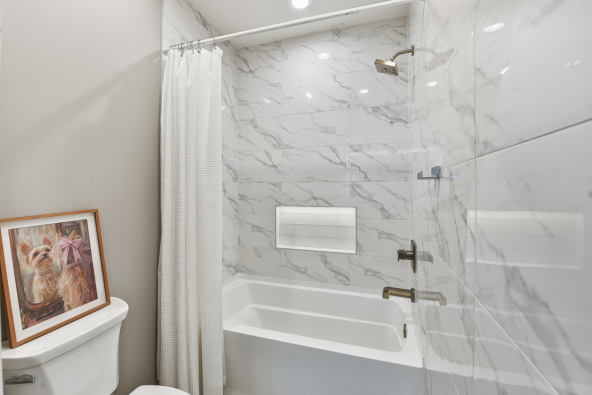 Marble tile tub surround with illuminated niche and glass enclosure