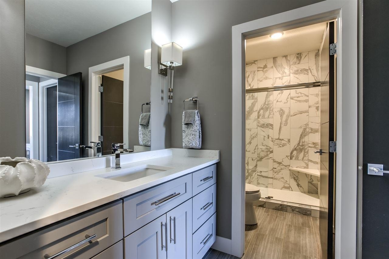 White vanity with quartz countertop and marble tile shower