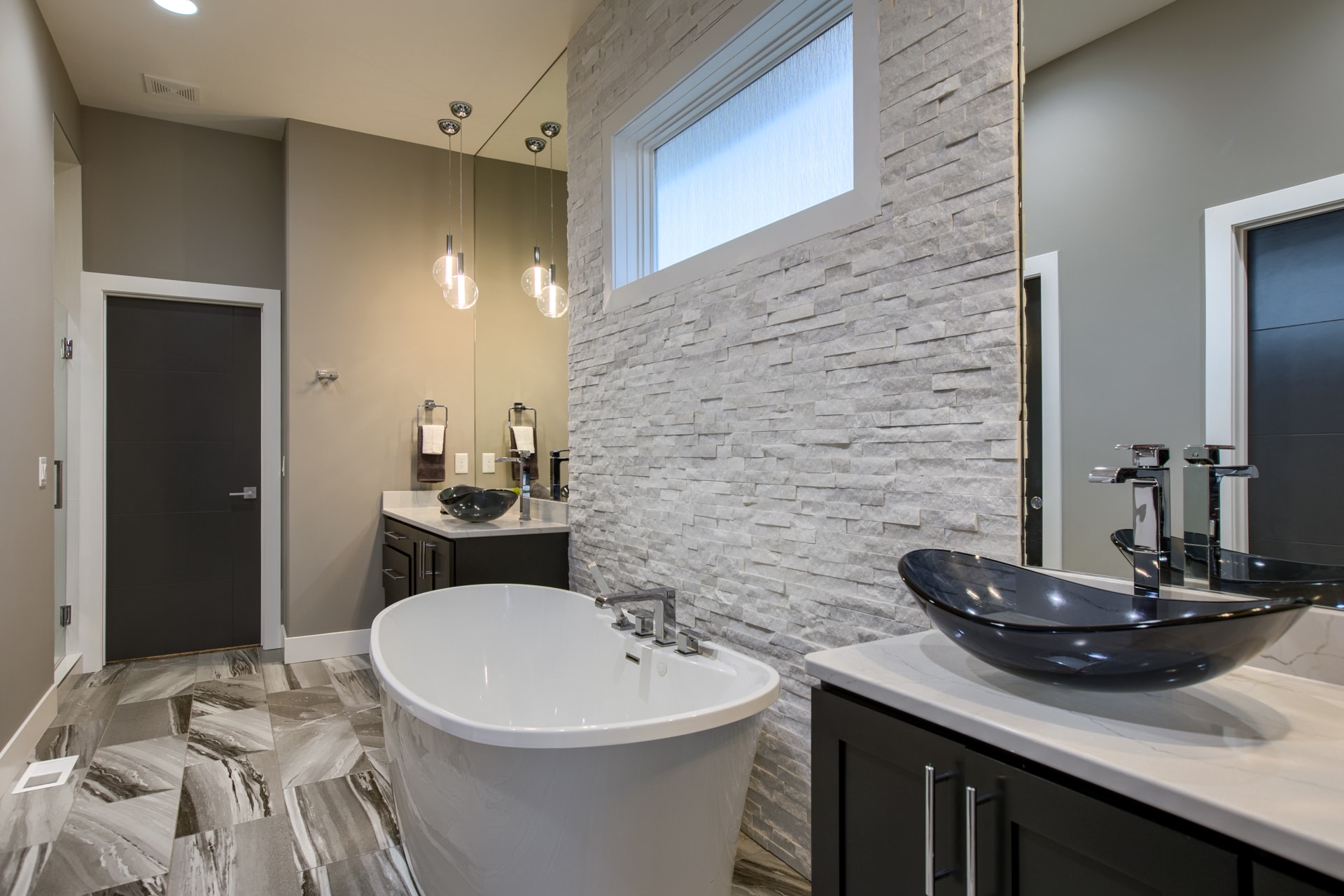 Luxury bathroom with freestanding tub, stone accent wall and marble tile floor