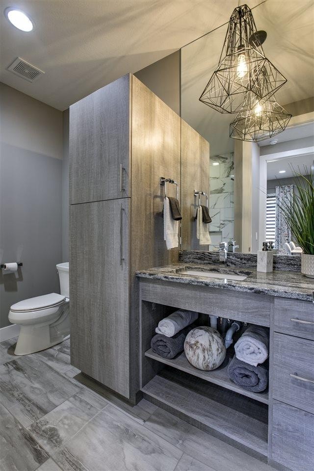Modern vanity with wood cabinetry, granite countertop and geometric pendant lighting