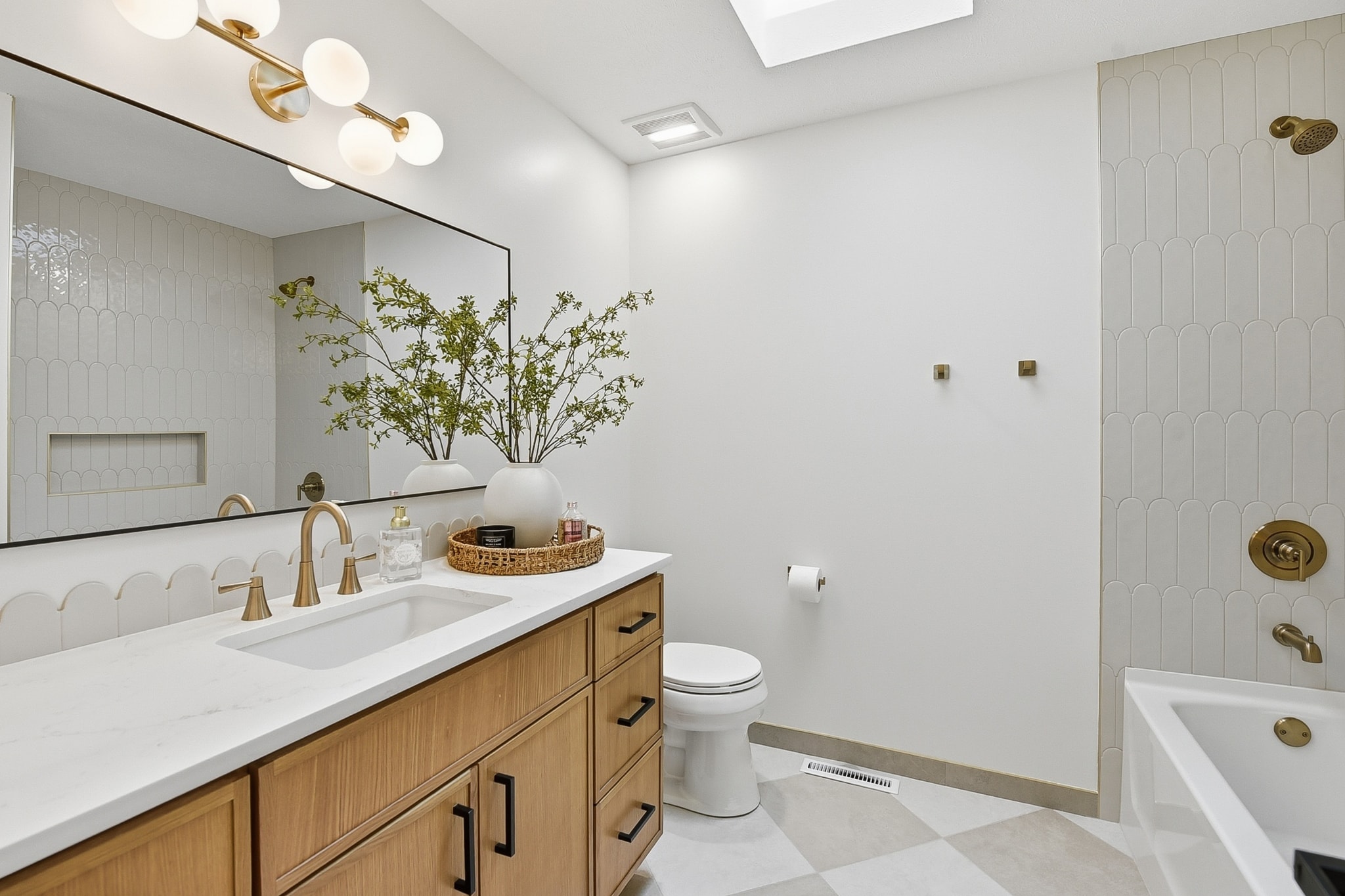 Spa-style bathroom with white tile, natural wood cabinetry and brass fixtures