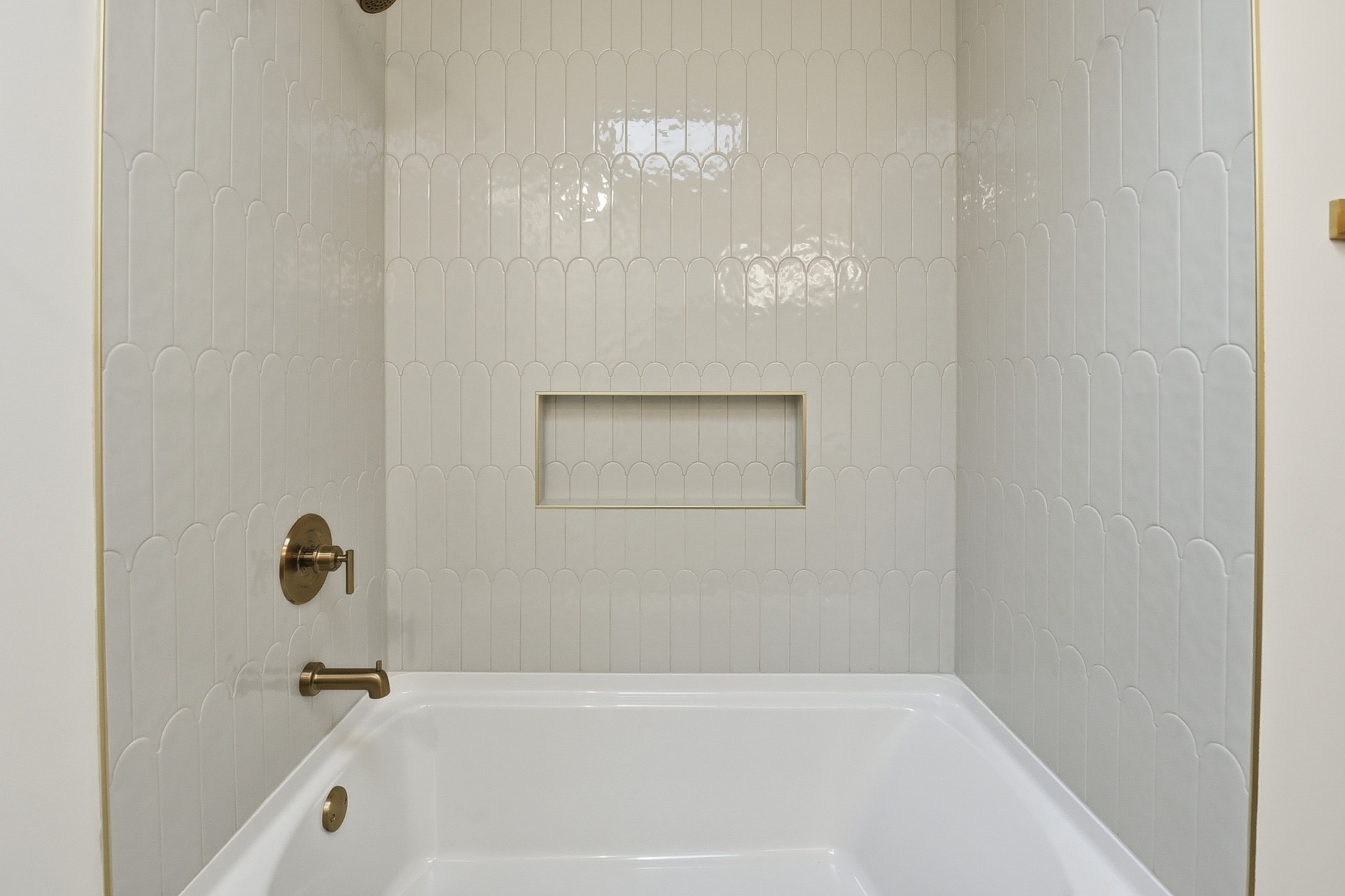Shower with white subway tile, brass fixtures and built-in niche