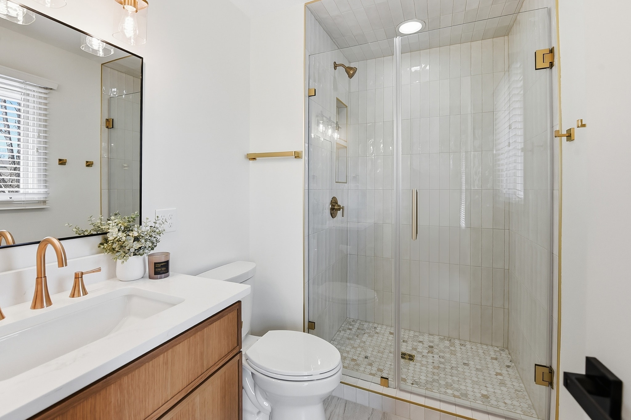 Modern bathroom with scallop tile, brass fixtures and glass shower enclosure