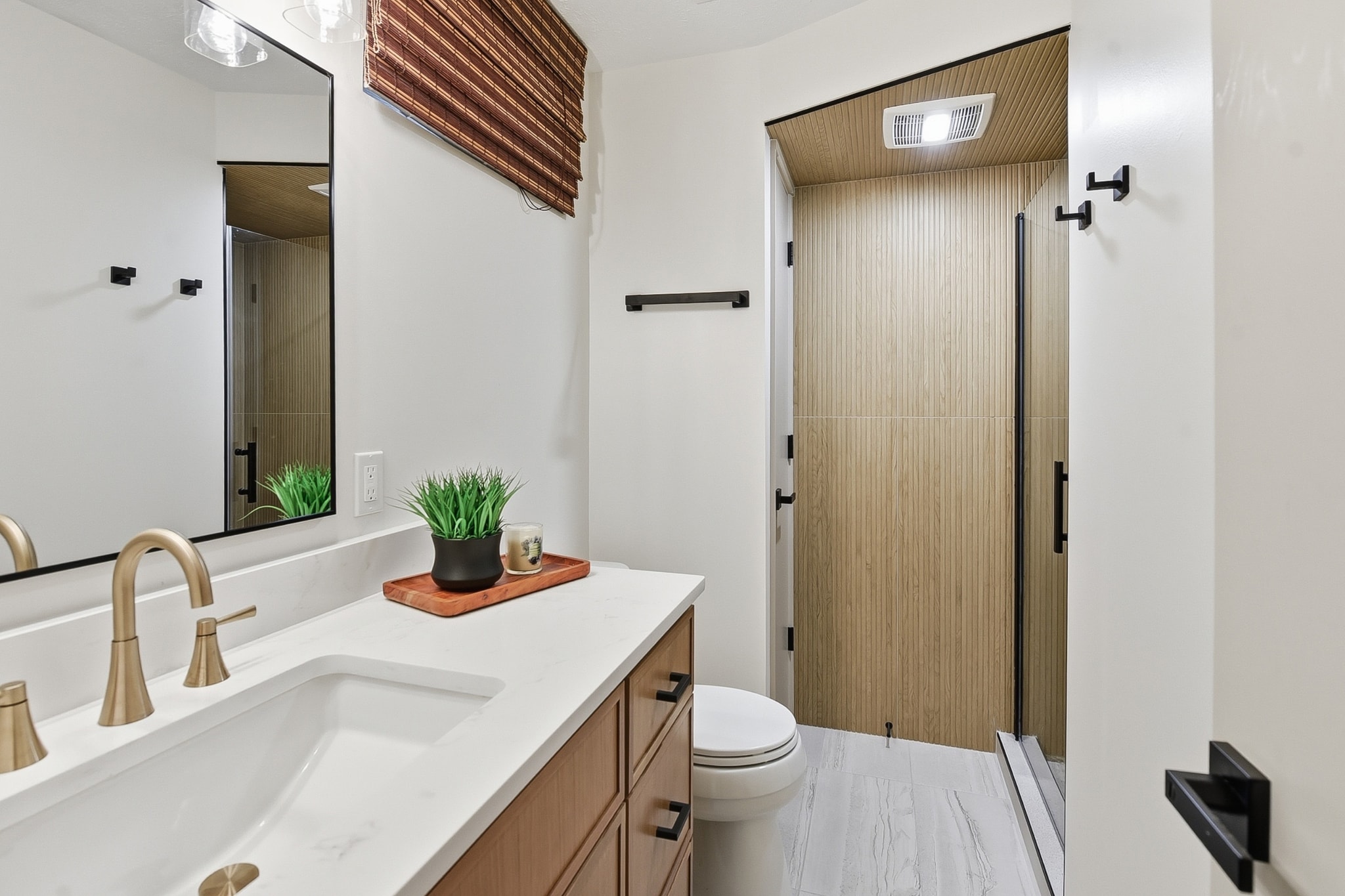 Bathroom with wood-look tile shower, gold fixtures and marble floor