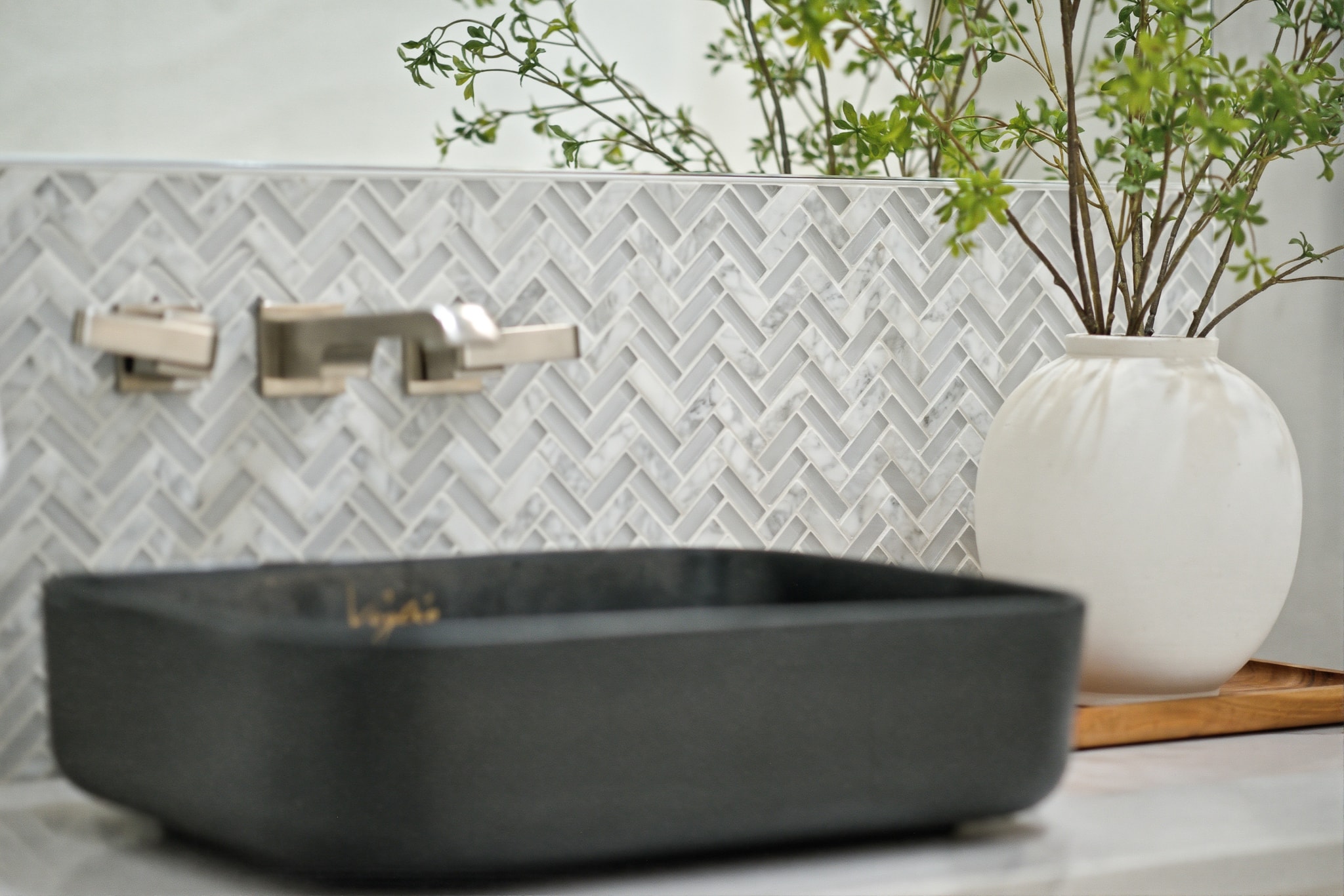 Close-up herringbone tile backsplash with vessel sink