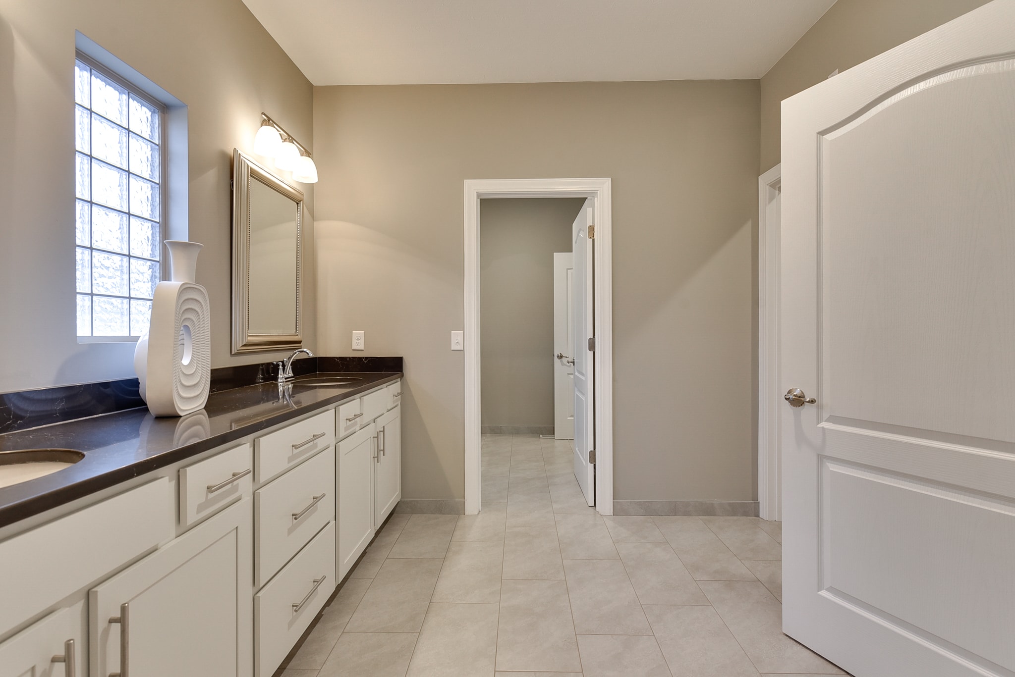 Single vanity with white cabinetry, dark granite countertop and large format tile floor