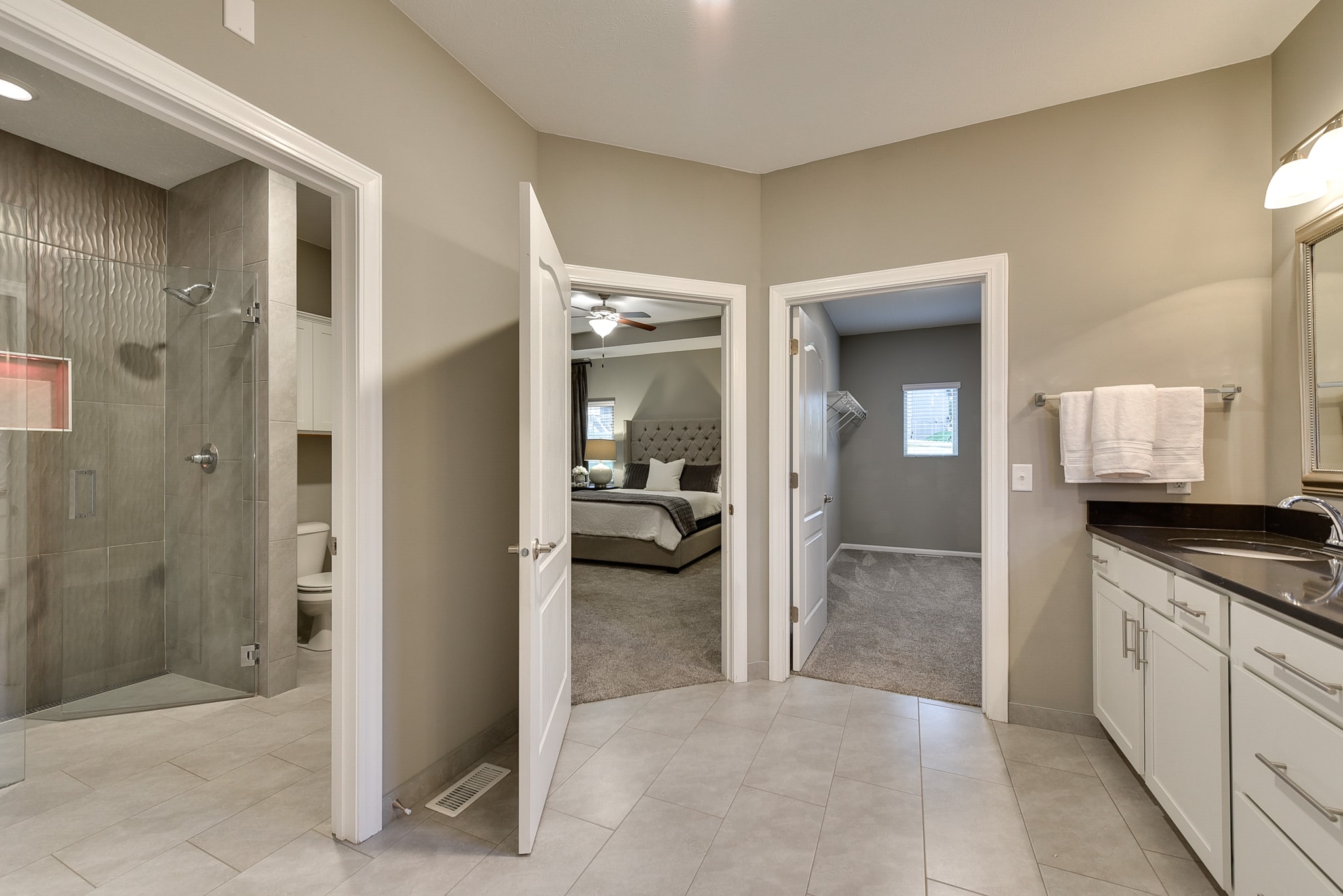 Master bath with glass shower enclosure, white vanity and large format tile floor