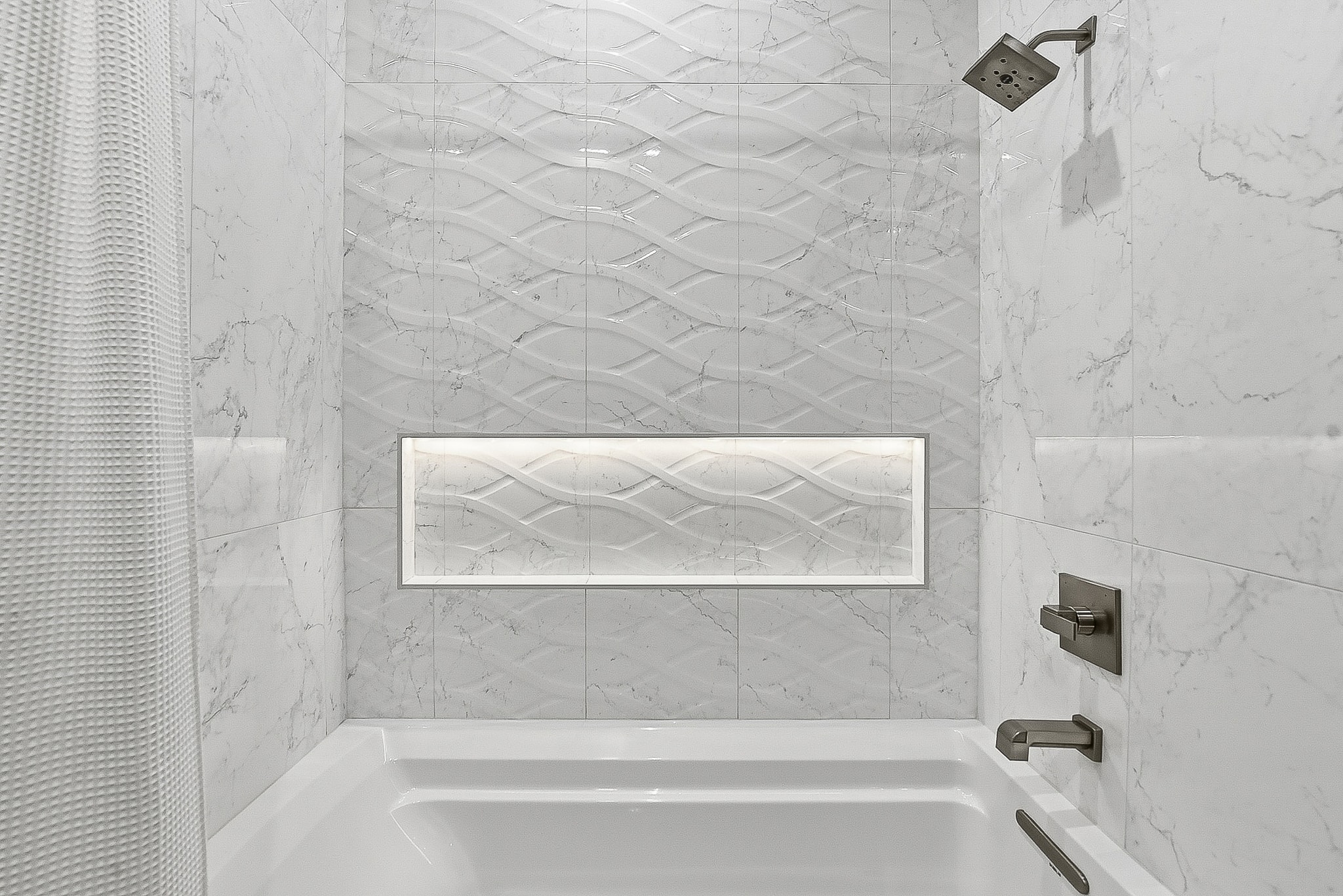 Marble tile tub surround with wave accent tile and niche
