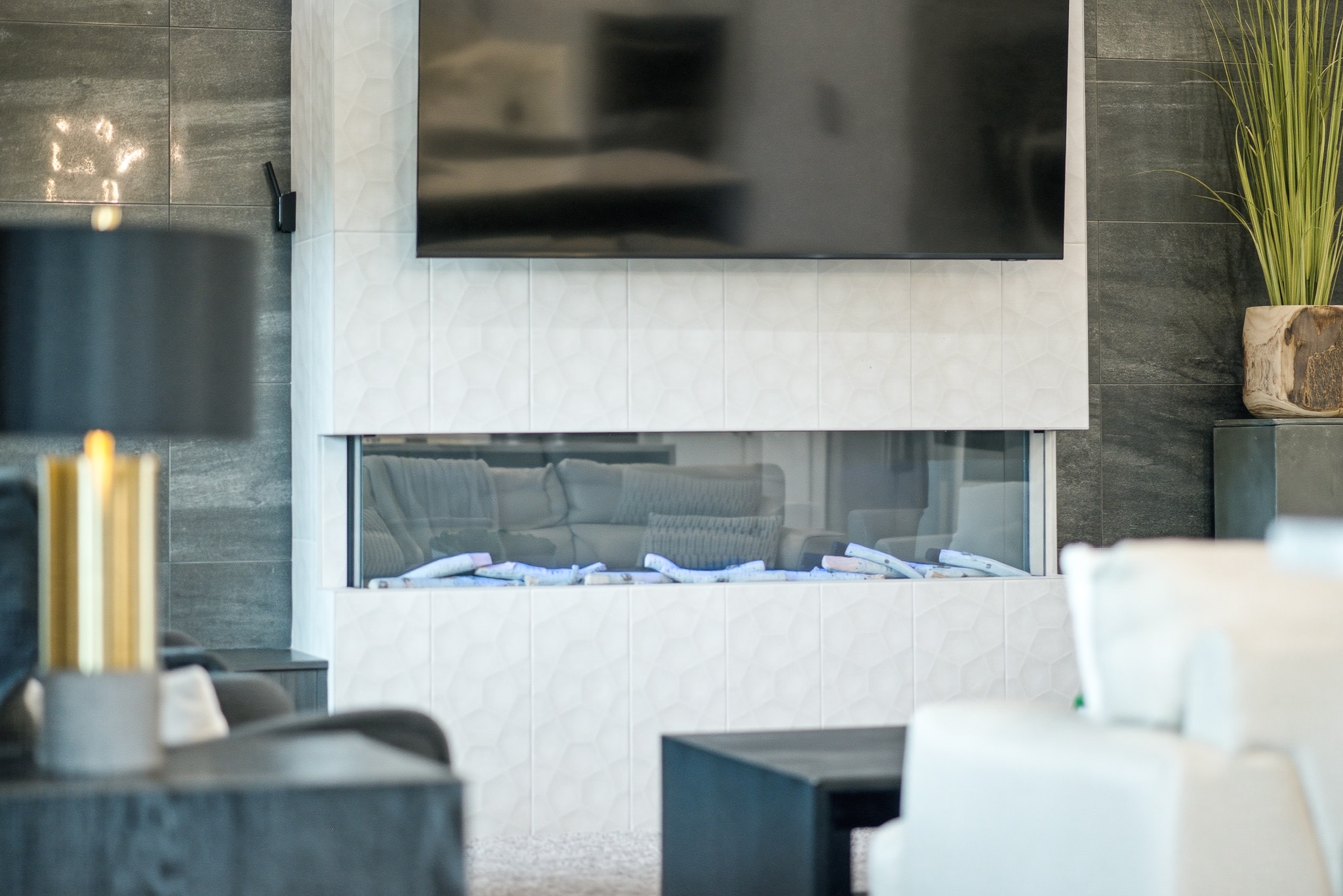 Close-up of white geometric tile fireplace surround with wall-mounted TV