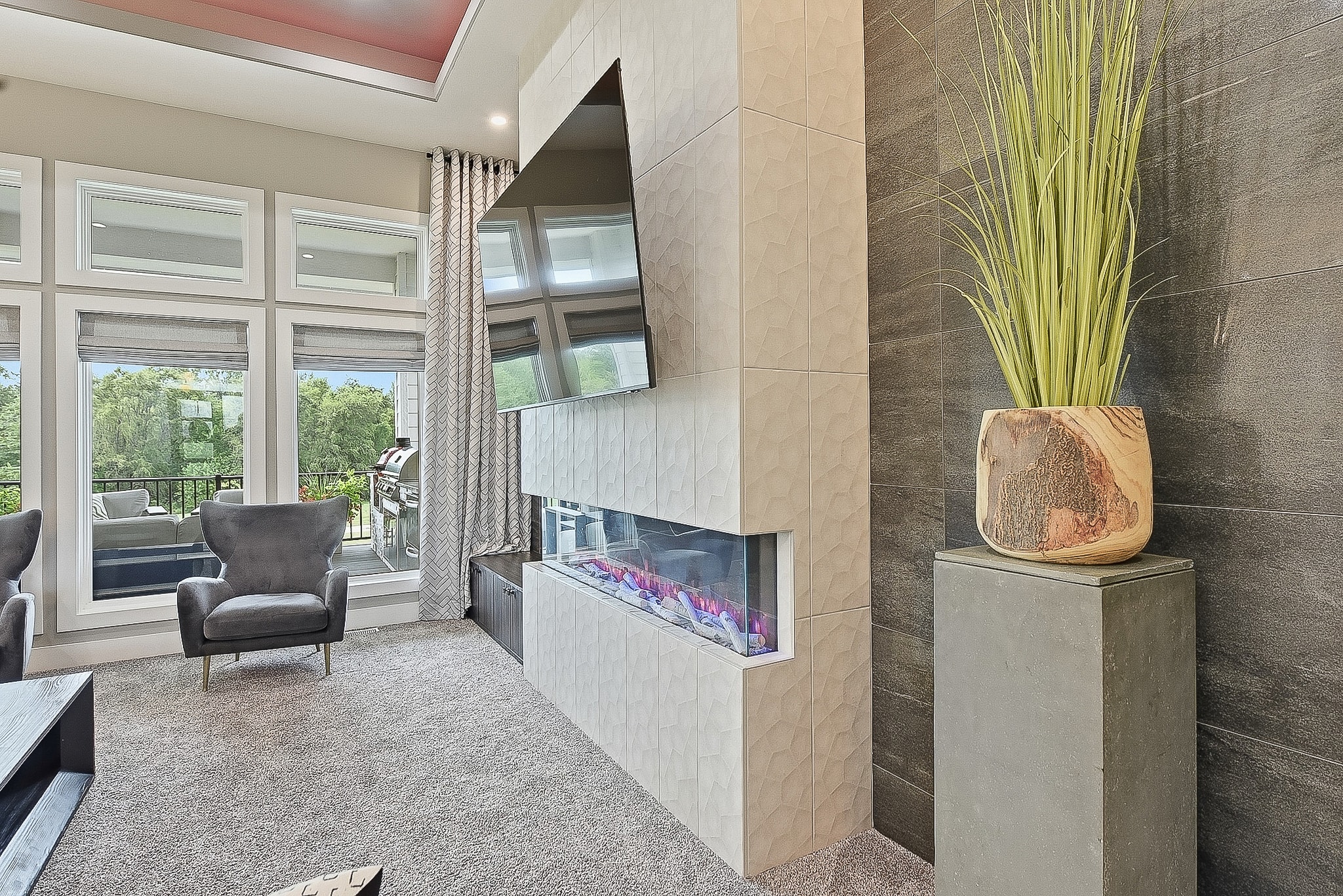 Angled view of white geometric tile fireplace column with dark stone accent wall