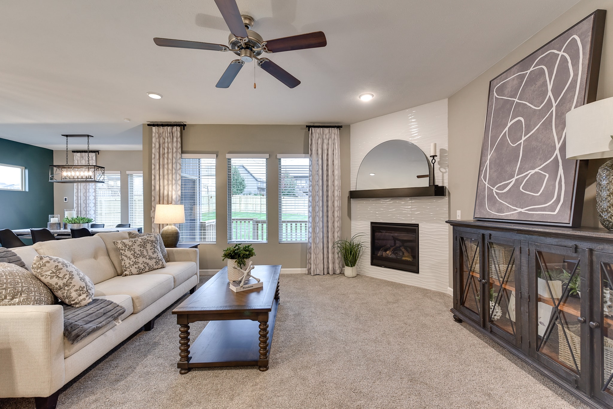 Living room with white wave tile corner fireplace and neutral decor