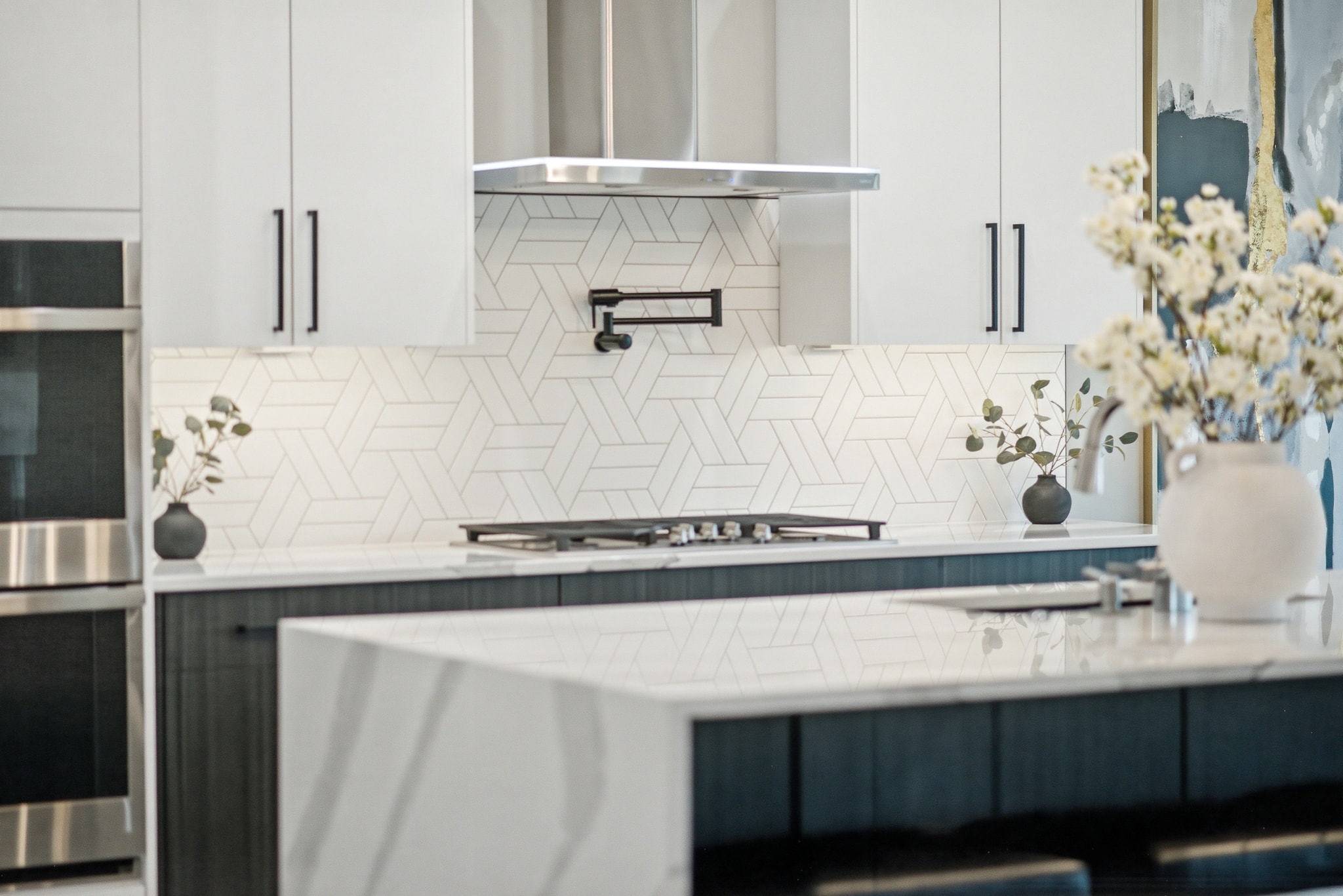 Modern kitchen with white geometric tile backsplash, dark lower cabinets and marble island