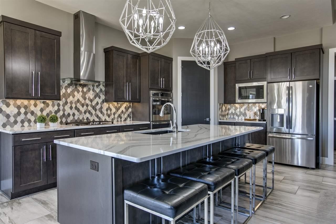 Dark espresso kitchen with diamond tile backsplash, marble island, black barstools and double wall ovens