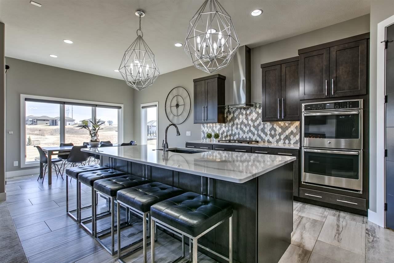 Dark espresso kitchen with diamond tile backsplash, marble island and geometric pendant lights at dusk