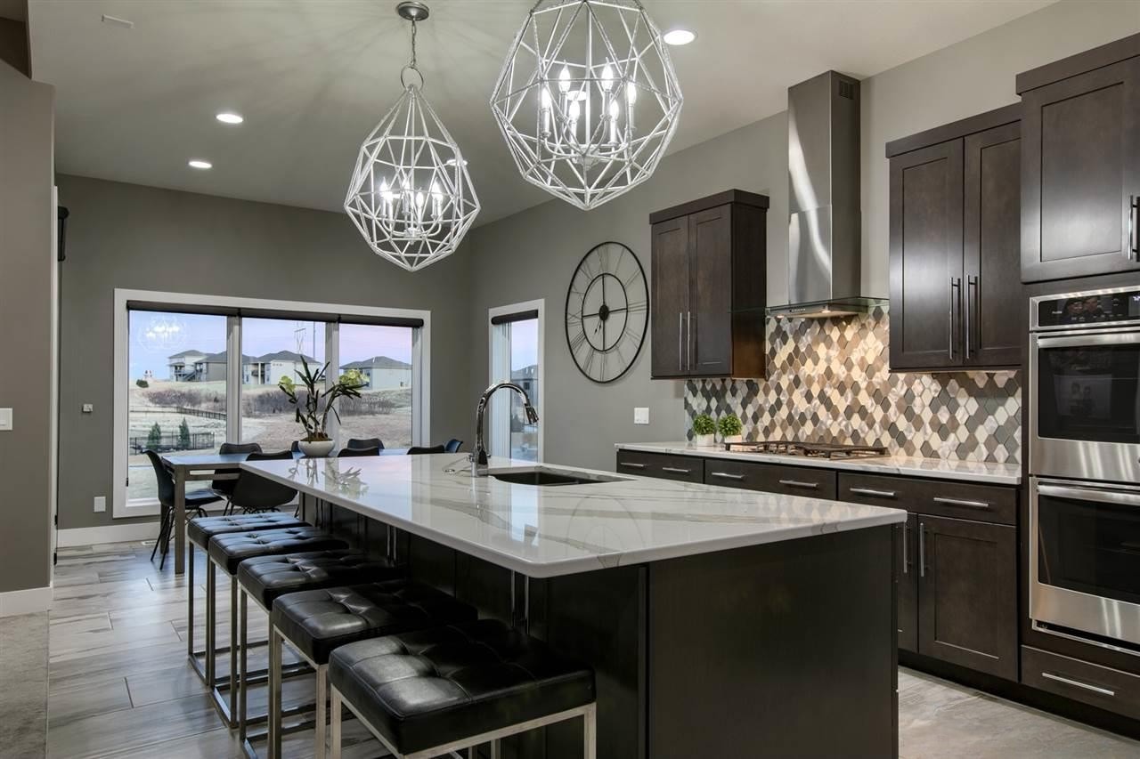Gray kitchen with diamond tile backsplash, marble island, farmhouse sink and dining area with large windows