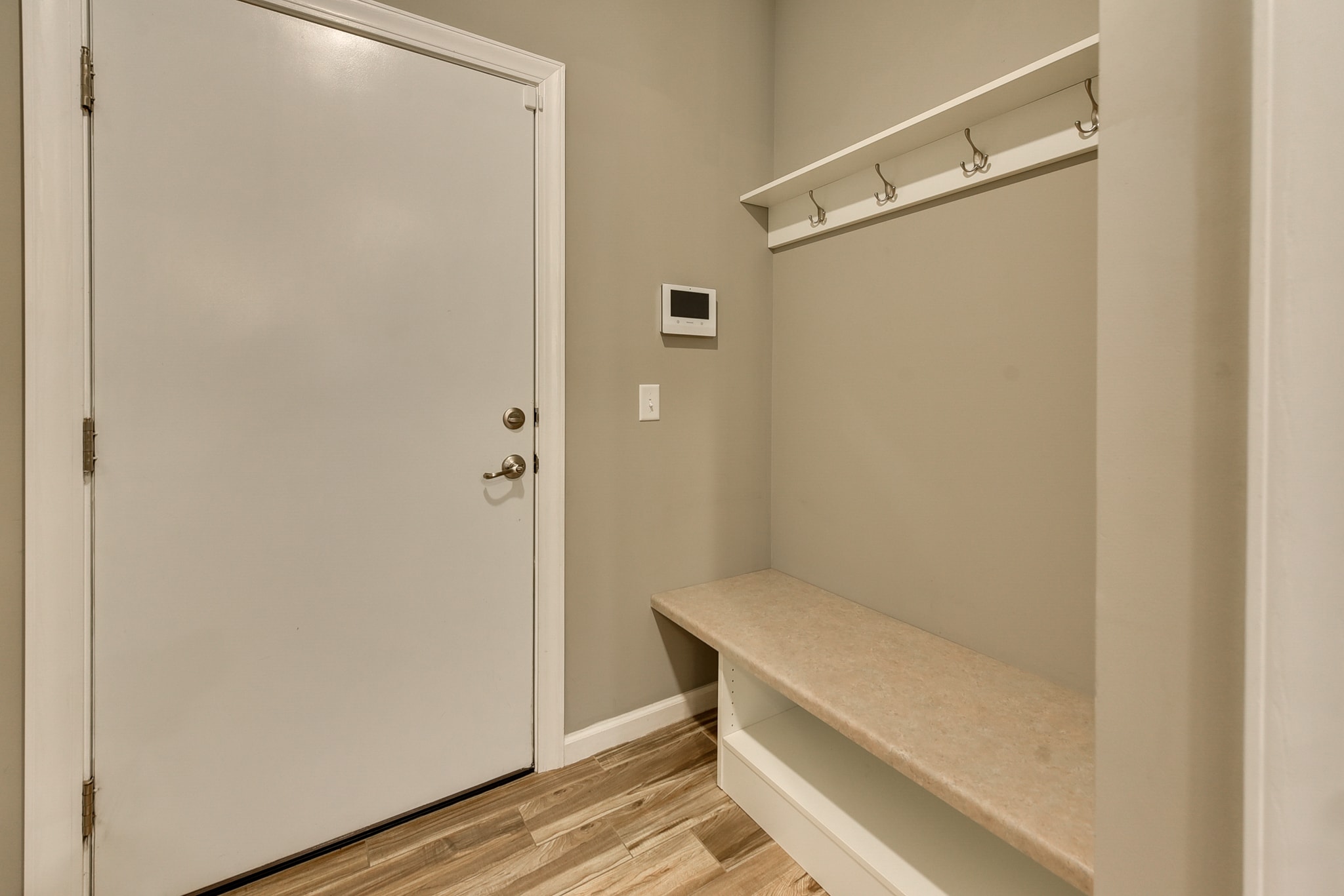 Mudroom entryway with tile floor, built-in bench, coat hooks and white door