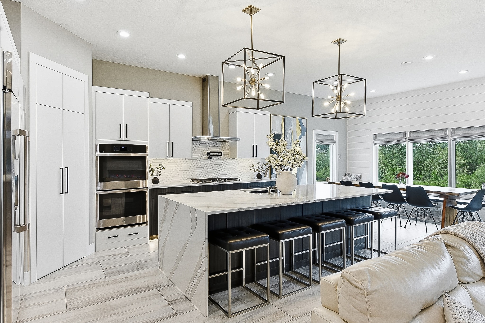 Open concept kitchen with white cabinets, geometric tile backsplash, marble island and pendant lighting