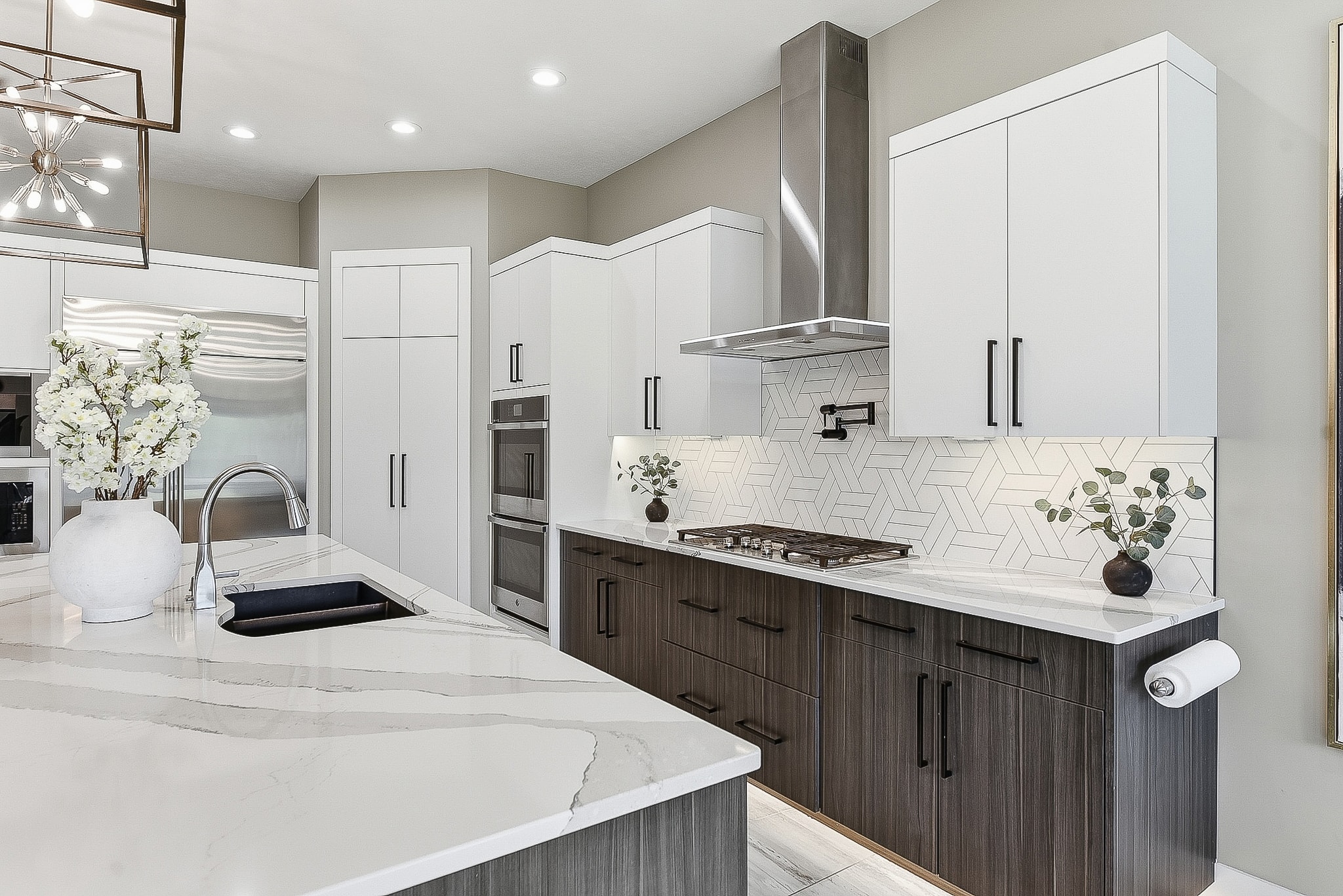 Full kitchen view with white upper cabinets, dark lower cabinets, geometric tile backsplash and marble countertops
