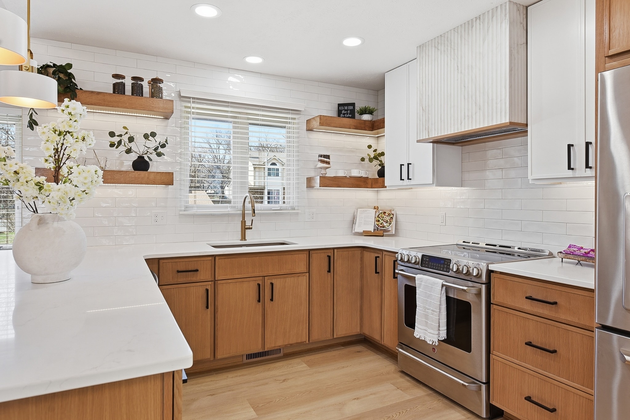 Farmhouse kitchen with white subway tile backsplash, warm wood cabinetry, open shelving and brass pendant lighting