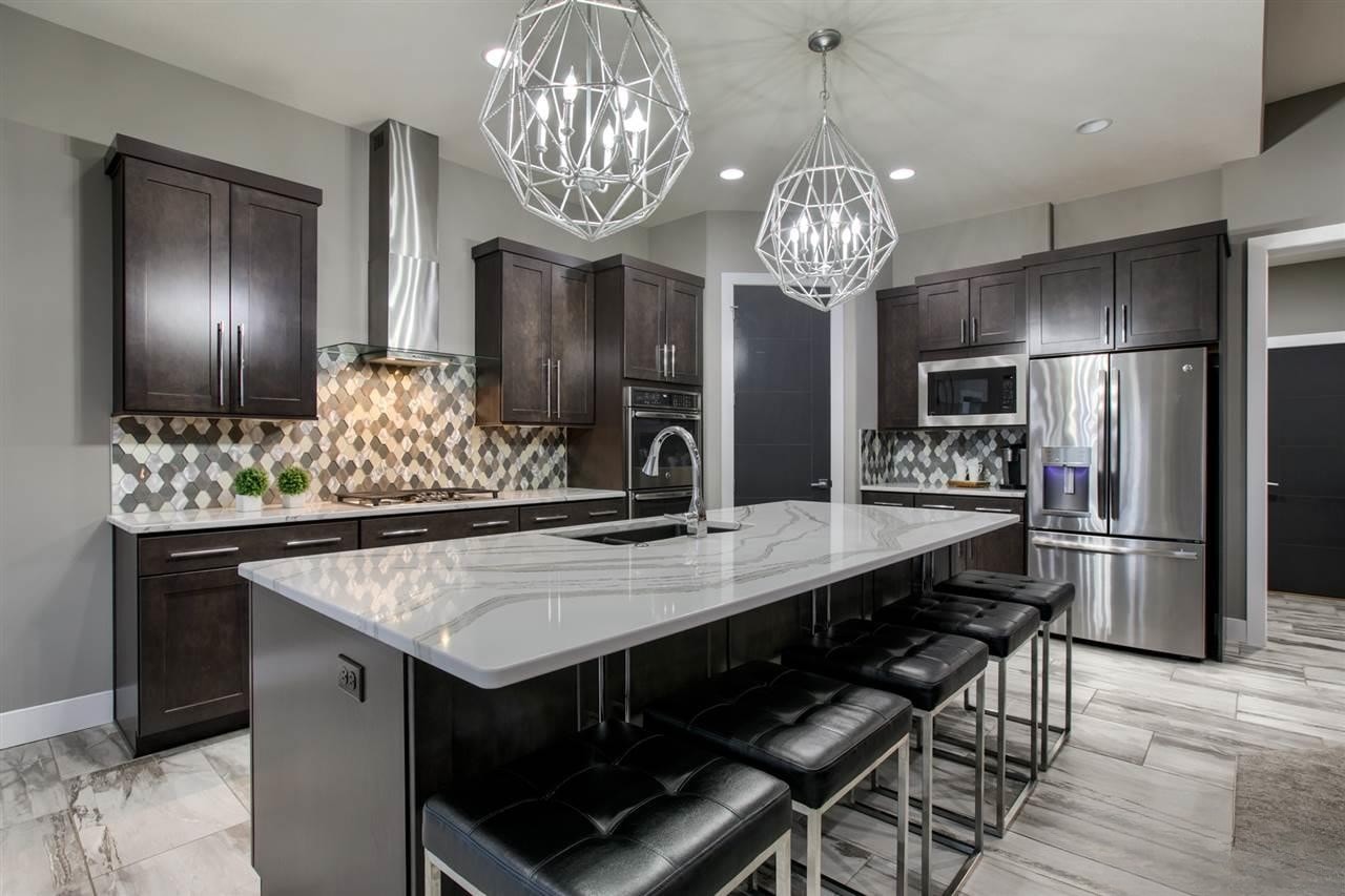Dark espresso kitchen with diamond tile backsplash, marble island, black barstools and geometric pendant lights