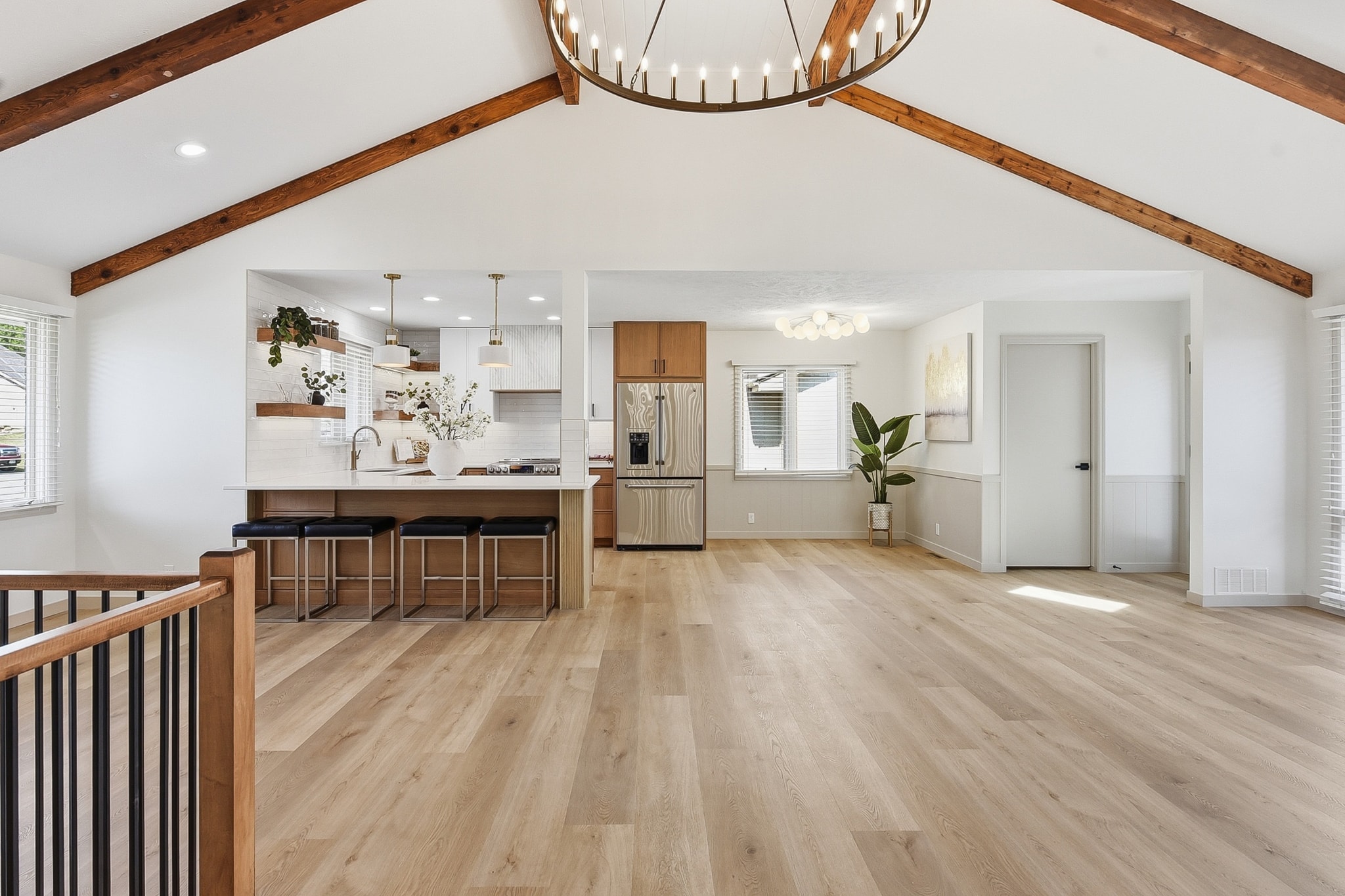 Open concept kitchen and living room with light oak LVP flooring and wood beam ceiling