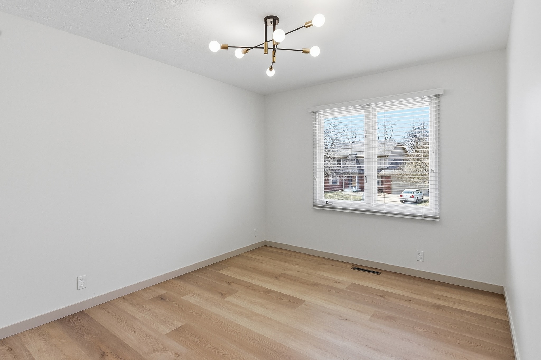 Bright bedroom with light LVP flooring, sputnik chandelier and window