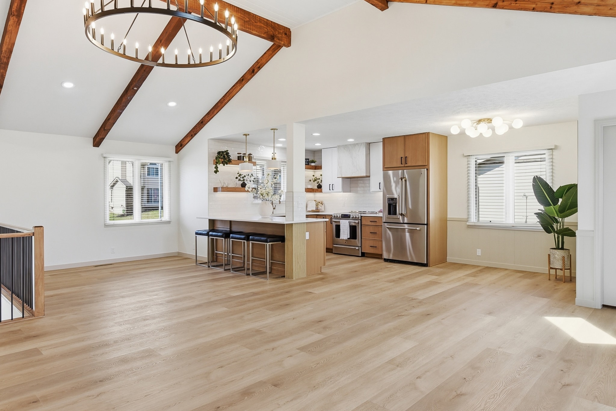 Open concept kitchen and living area with light LVP flooring and wood beam vaulted ceiling