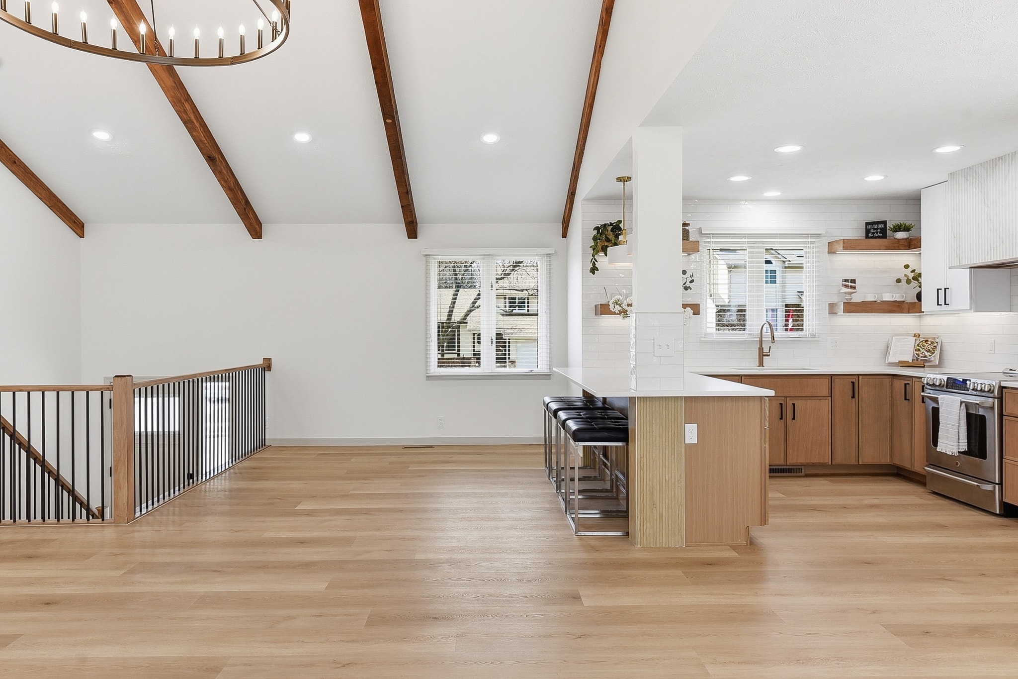 Kitchen and open living space with LVP flooring, wood beams and staircase railing