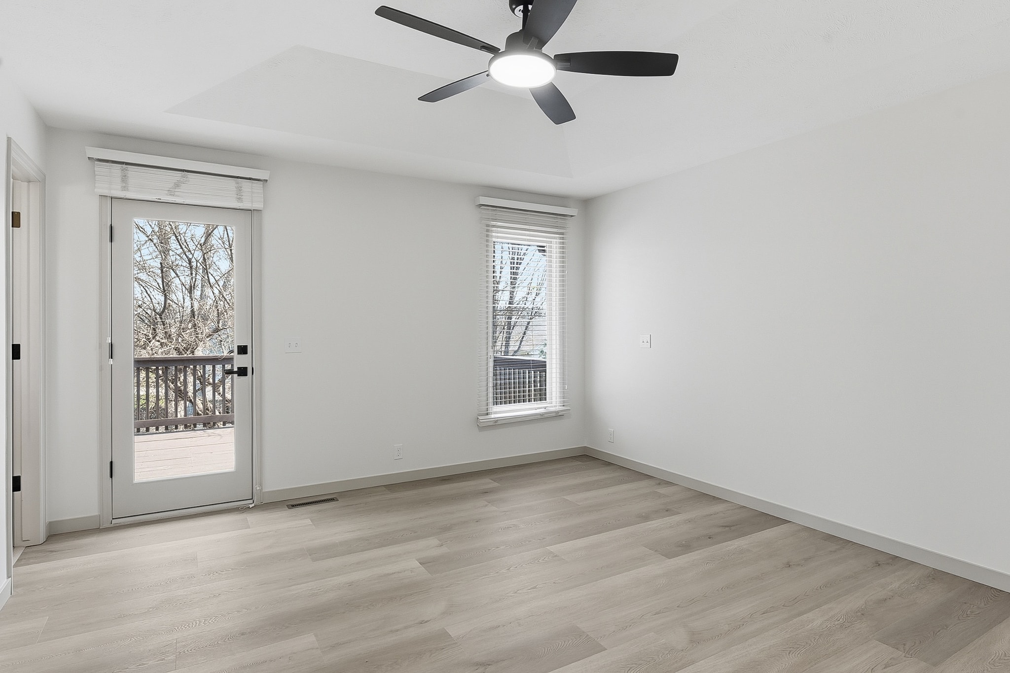 Bedroom with LVP flooring, ceiling fan and sliding door to deck