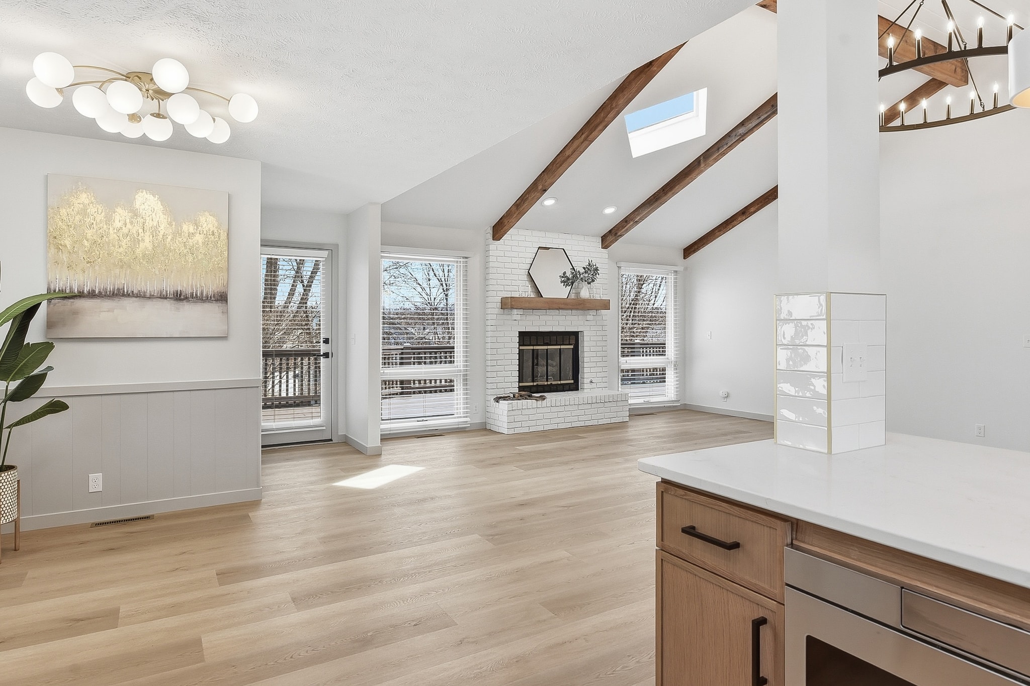 Living room with LVP flooring, white brick fireplace and kitchen view